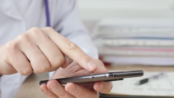 Manos masculinas del médico médicalc escribiendo mensaje SMS en el teléfono inteligente. — Vídeo de stock