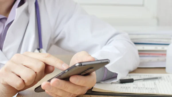 Mannelijke handen van medische arts typen SMS-bericht op smart phone. — Stockfoto
