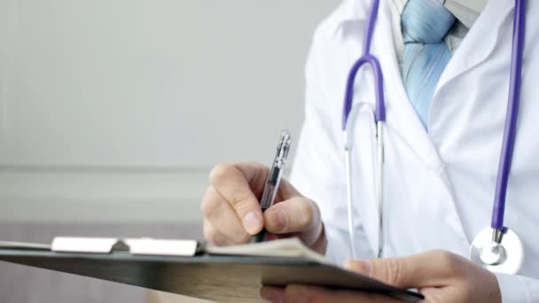 Lekarz, pisanie notatki pacjenta na badania lekarskie — Wideo stockowe