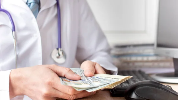 Male medicine doctor holding in hands bunch of dollars banknotes — Stock Photo, Image