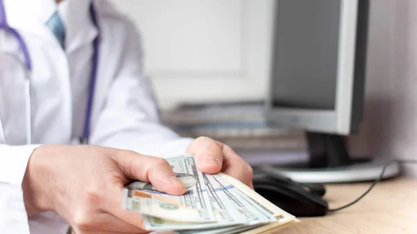 Male medicine doctor holding in hands bunch of dollars banknotes — 스톡 사진