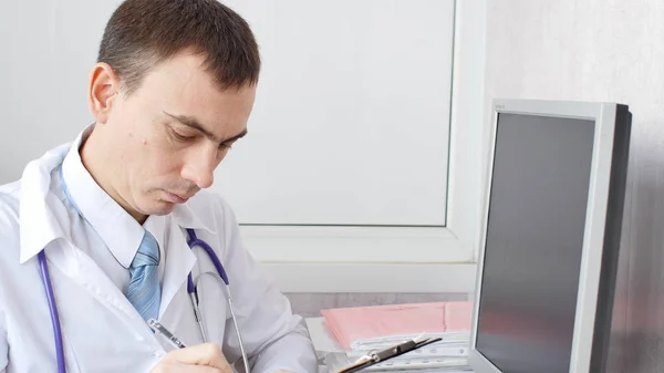 Лікар пише нотатки пацієнта на медичному огляді — стокове фото