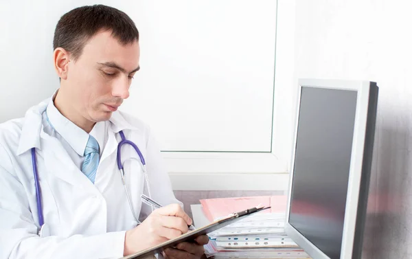 Лікар пише нотатки пацієнта на медичному огляді — стокове фото