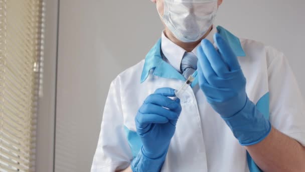 Médico con máscara médica y guantes azules preparándose para la inyección . — Vídeo de stock