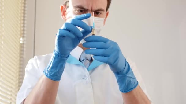Lékař v lékařské masce a modrých rukavicích připravuje k injekci. — Stock video