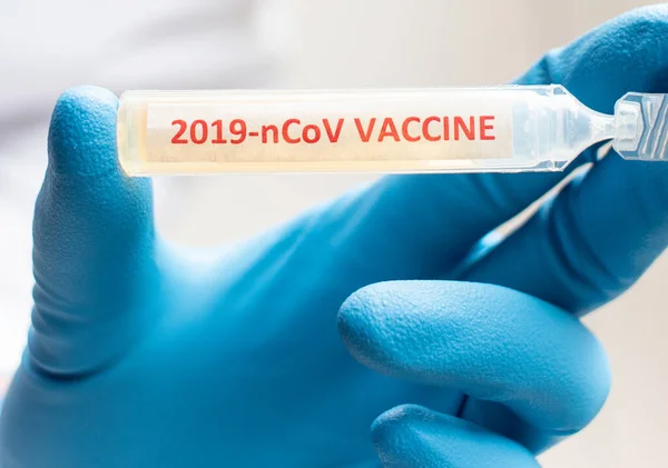 Médico ou laborante segurando tubo com a vacina nCoV Coronavirus — Fotografia de Stock