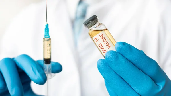 Medical doctor or laborant holding tube with nCoV Coronavirus COVID vaccine