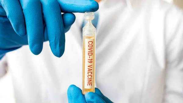 Medical doctor or laborant holding tube with nCoV Coronavirus COVID vaccine