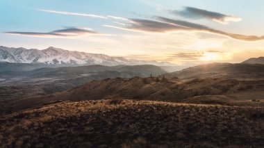 Tepeler ve gün batımında karlı dağlar