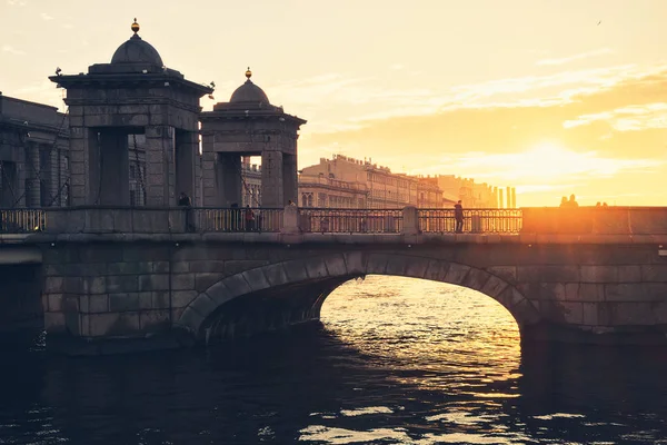 Günbatımı/insanlar yürüyüş boyunca Lomonosov köprü gün batımında, St. Petersburg şehir Köprüsü