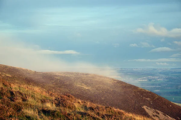 De wolk zonk laag op de heuvels en wordt verlicht door de stralen o — Stockfoto