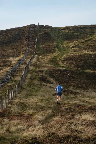 En kvinna springer bland de skotska kullarna i parken — Stockfoto