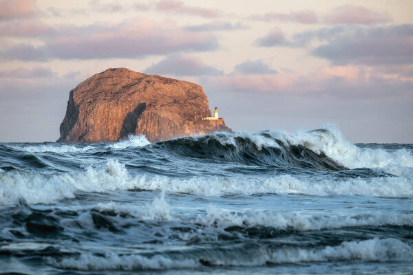 Storm waves and lighthouse on a cliff