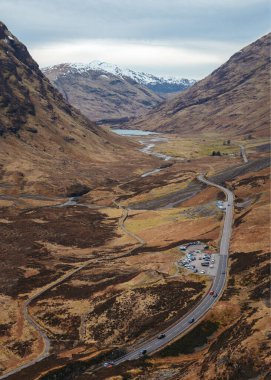 Dağ vadisinden geçen arabaların olduğu bir yol manzarası. Glen Coe 'nun İskoç Dağları