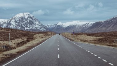 Glen Coe 'nun İskoç Dağları' ndan geçen bir yol, karlı dağlar ve vadi. İskoçya