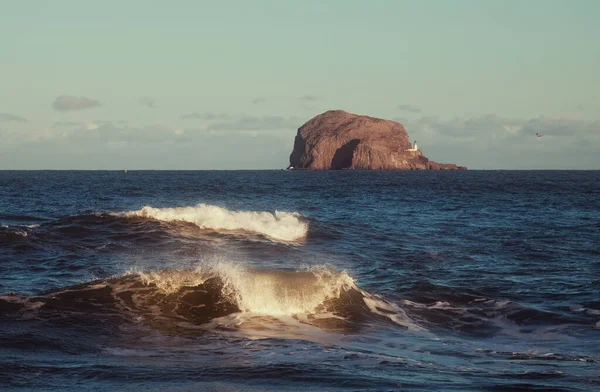 Ondas do mar e farol em um penhasco em um pôr do sol — Fotografia de Stock