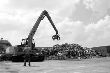 Black and white photo of a small crane loading recycling plant