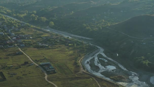 Село в горах, річка і зелені дерева, вид з повітря — стокове відео