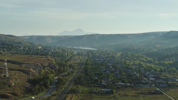 Деревня в горах, железная дорога, линии электропередач, вид с воздуха — стоковое видео