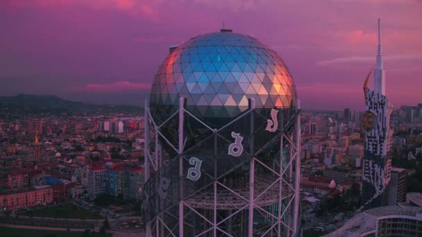 Батуми, Грузия - 2018: вид с воздуха - Алфавитная башня на фоне небоскребов на закате — стоковое видео