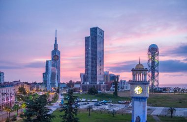 Batumi, Gürcistan - 2018: Deniz feneri sette, gökdelenler gün batımında