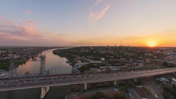 Тімелапс на заході сонця зверху: рух на мосту над річкою — стокове відео