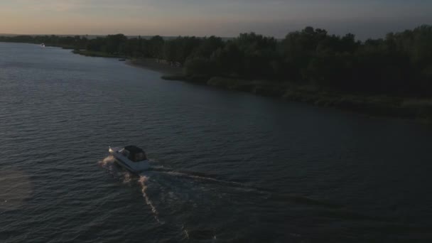 Pequeño barco blanco corre a lo largo del río al atardecer, vista aérea — Vídeo de stock