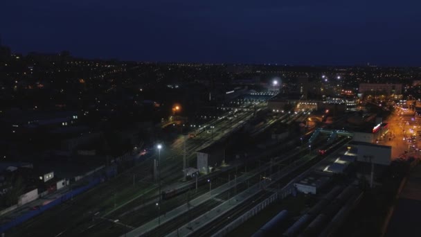 Залізничний вокзал вночі, рейки і поїзди, вид з повітря — стокове відео