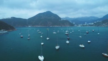 Aerial view: white yachts in the sea bay, mountains and a city in the distance