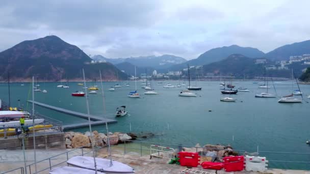 Yachts in the sea bay, long masts, clear water, around the mountain, aerial view — Stock Video