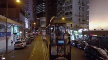 Hong Kong, China - 2020: Double-decker trams ride down the street at night