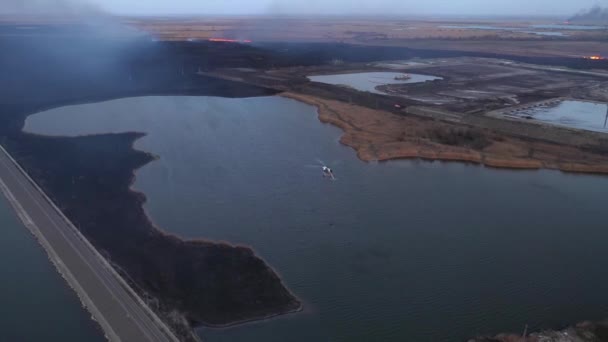 Fire helicopter draws water in a lake, aerial view — Stock Video