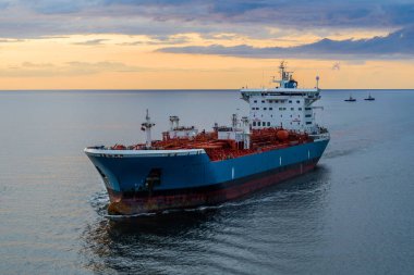 Denizde bir tanker, hava manzaralı. Gün batımında körfezde büyük mavi beyaz bir gemi..