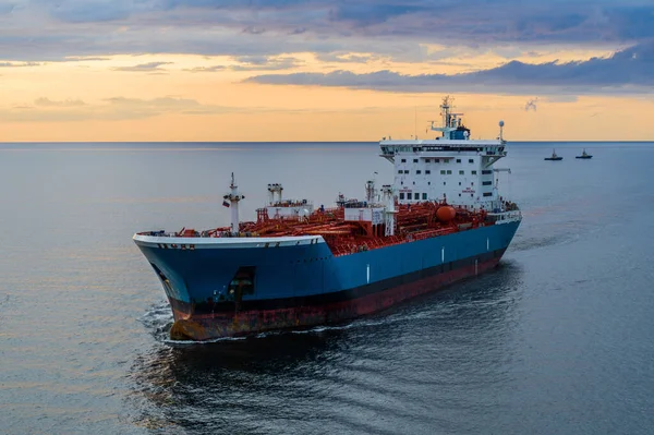 Denizde bir tanker, hava manzaralı. Gün batımında körfezde büyük mavi beyaz bir gemi..