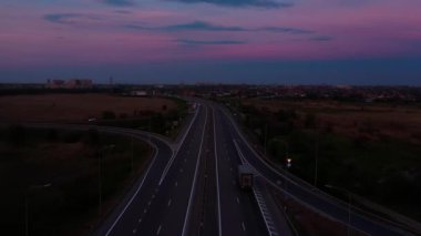 Gün batımında otoyol, arabalar ve kamyonlarla dolu yol.