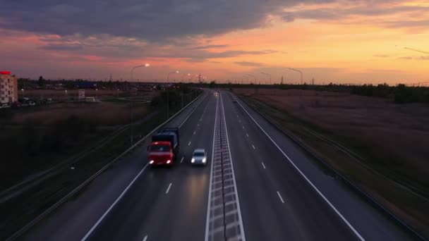 Autostrada o zachodzie słońca z góry, droga oświetlona latarniami, dramatyczne niebo — Wideo stockowe