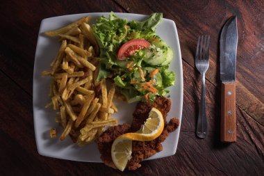 patates kızartması, schnitzel ve salata plaka üzerinde 