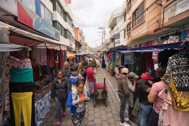Otavalo, Ecuador-Mart 31,2018: Pazar gününde sokakta ayarlanan satıcı standları insanlar yürüyüş