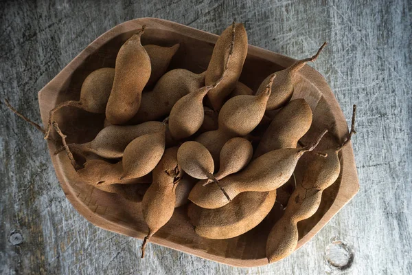 Цілі фрукти тамаринда в дерев'яній мисці — стокове фото