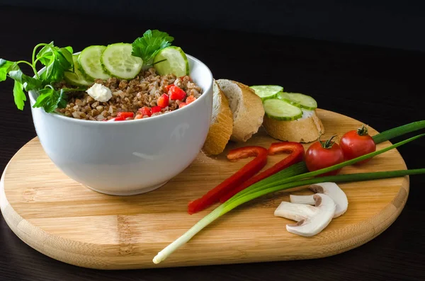 Siyah arka planda, yan görünüm buğday lapası taze sebze ile dolu kase