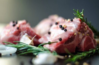 Çiğ et kemik ve biberiye, soğan halkası ile? ve sarımsak, koyu arka plan, yan görünüm