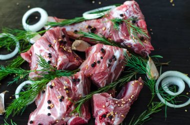 Çiğ domuz etli kemikler ve dere otu, biberiye, sarımsak ve kara biber