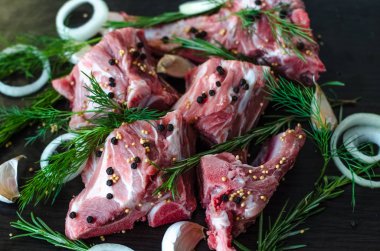 Dere otu, biberiye, sarımsak ve baharat siyah zemin üzerine karabiber ile kemikler üzerinde çiğ et