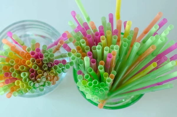 Colorful drinking straws for celebrations in green and clear glass, on bright background