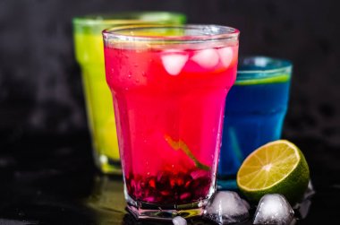 Üç renkli kokteyller, kireç ve siyah arka plan üzerine buz