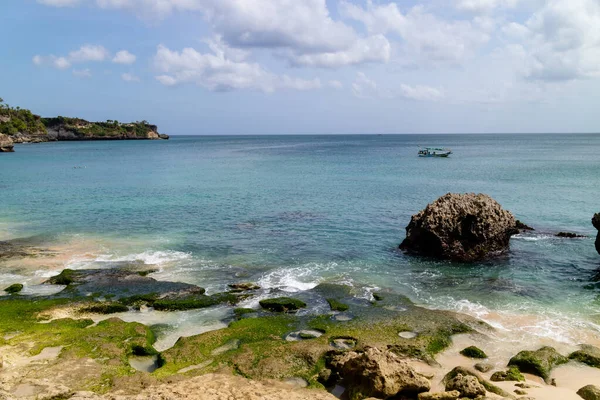 Sahilin manzarası ve arka planda yüzen bir tekne.