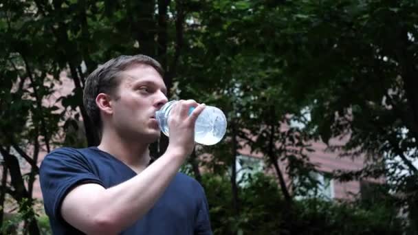 A man drinking from a clear plastic bottle — Stock Video