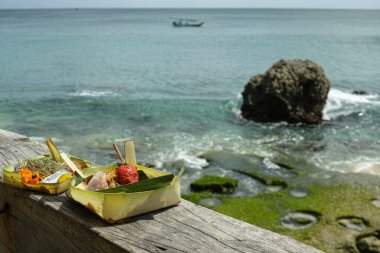 Tropikal kıyı şeridinin önünde meyve ve tütsü sunan Bali dini adakları