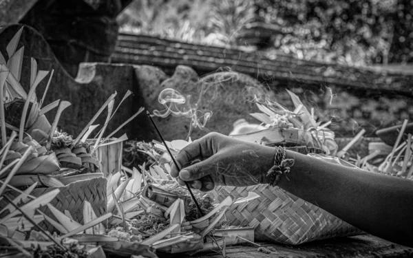 A hand placing burning incense in an offering at a Balinese temple — Stock Photo, Image