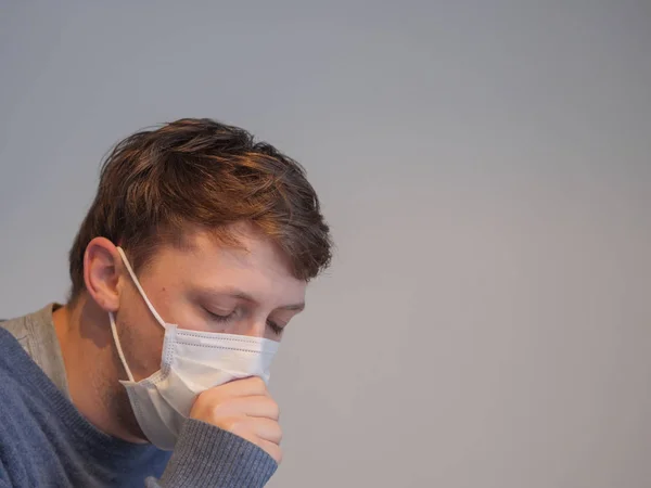 Un bel giovanotto che indossa una maschera con l'influenza — Foto Stock